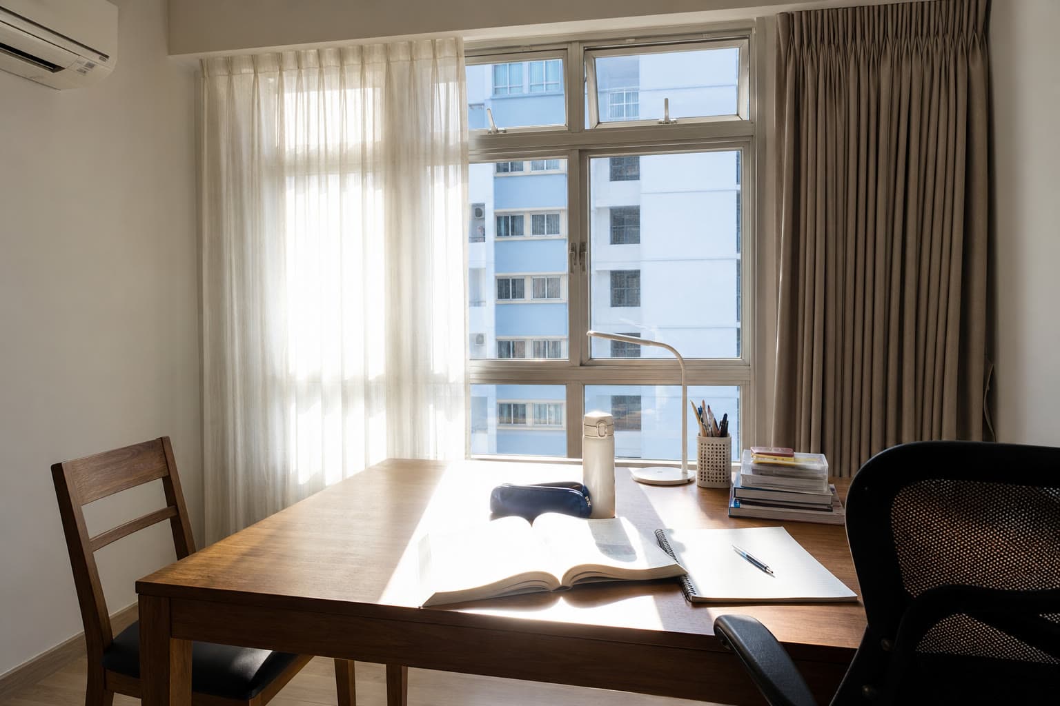 Afternoon sun on an HDB dining table used as a study desk, with sheer day curtains and a stacked blackout night curtain on a casement window.